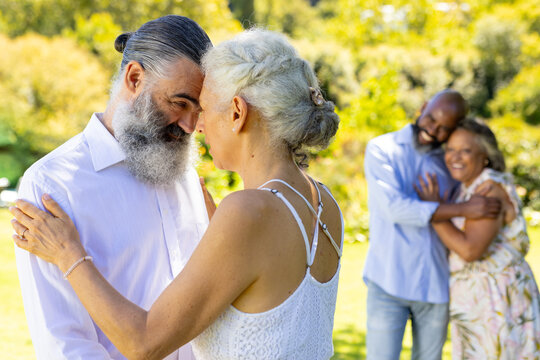 Senior bride and groom dancing and embracing at outdoor wedding, enjoying time together in park