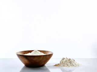 Wooden bowl filled with flour on a white surface