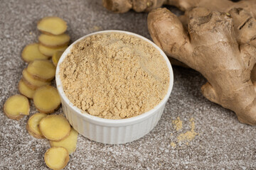 Ground ginger root powder natural spice seasoning on gray stone background