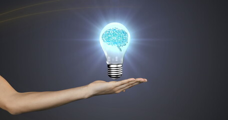 Image of human brain spinning inside a electric bulb over cupped hand against grey background