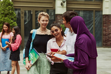 Students, boys and girls from different cultures working on their homework in front of the university, discussing tasks. Concept of education, university, multicultural students, unity