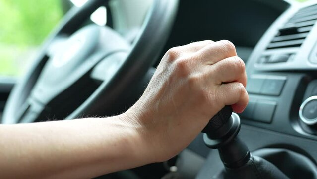 Close-up of driver change speed holding hand on gearbox car. Woman's hand at gearshift in car