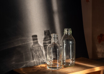 Still life with glass bottles, quiet shadows in the background, soft evening light