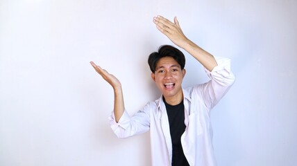 Excited young Asian man gestures pointing upwards using the palm of his hand