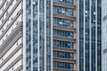 Fototapeta premium A beautiful background of an glass office building, reflecting clouds in the opened windows