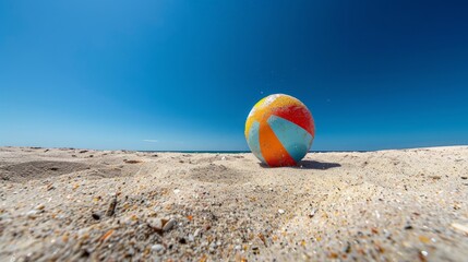 Obraz premium Sunny Day Fun: Beach Ball Rolling on Sand - Worm's Eye View with Vibrant Colors and Clear Blue Sky