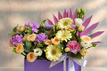 Bouquet of assorted flowers arranged in a purple box, showcasing a blend of colors and scents that exude elegance and beauty.