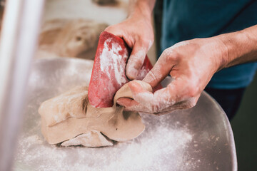 cutting raw bread dough on kitchen scales in traditional bakery