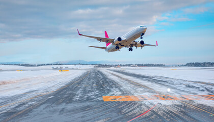 Commercical white airplane fly up over take-off runway the (ice) snow-covered airport- Norway