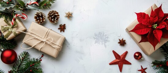 Fototapeta premium Christmas decorations arranged on a white backdrop with a gift box, pine branches, pine cone, festive stars, and a red poinsettia. The setting includes a blank greeting card and envelope for a mockup