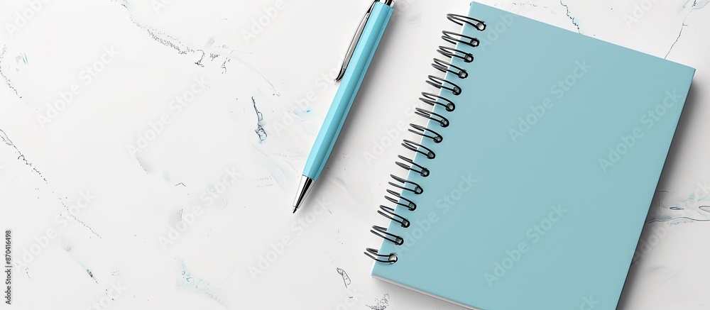 Poster top view of a light blue spiral notepad with a pen on a white desk background for your design, featu