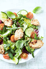 Salad with Chicken Breast, Cherry Tomatoes, Cucumber, Rocket and fresh Basil. Bright wooden background. Close up.	