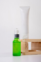 Green glass cosmetic bottle and hand, Skin care or sunscreen cosmetic with stylish props on white background.