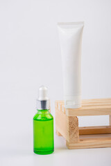 Green glass cosmetic bottle and hand, Skin care or sunscreen cosmetic with stylish props on white background.