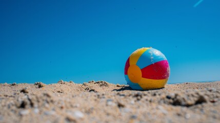 Obraz premium Sunny Beach Day: Colorful Beach Ball Stuck in Sand from Worm's Eye View
