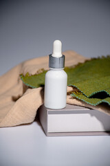 White glass cosmetic bottle and hand, Skin care or sunscreen cosmetic with stylish props on grey background.