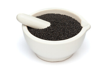 Close-up of Dry Organic Basil Seeds (Ocimum tenuiflorum) or Sabja Seeds, in white ceramic mortar and pestle, isolated on a white background.