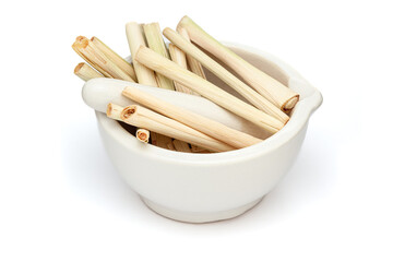 Close-up of Dry Organic lemongrass (Cymbopogon flexuosus), in white ceramic mortar and pestle, isolated on a white background.