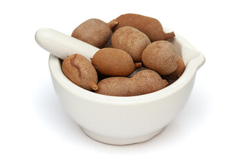 Close-up of fresh Organic Sweet Tamarind (Tamarindus indica) Fruit, in white ceramic mortar and pestle, isolated on a white background.