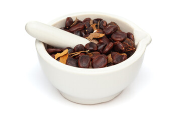 Close-up of Organic Tamarind (Tamarindus indica) seeds, in white ceramic mortar and pestle, isolated on a white background.