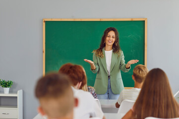 Teacher welcoming group of children on first day of school. Happy smiling friendly woman standing...