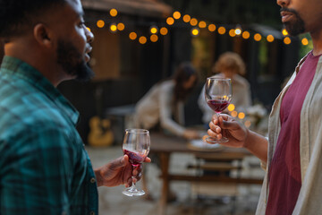 Two black men having a conversation holding wine glasses