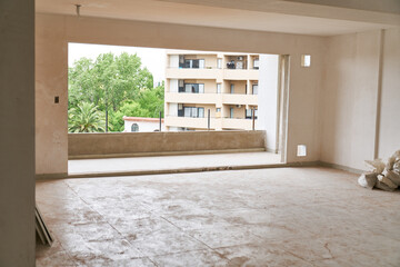Interior of incomplete house room with large balcony entrance at construction site
