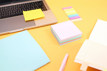 Flat Lay Of Reminder Sticky Note, Book And Laptop Over Yellow Background. Office Workers Equipment 