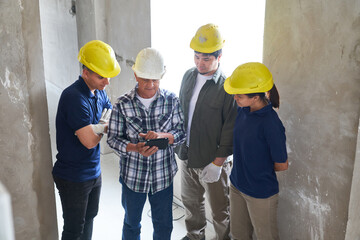 High angle view of senior contractor sharing tablet PC with workers while standing together at...