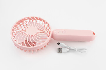 Mini electric pink fan with handle, isolated on white background. Portable electrical equipment that very useful when hot weather 