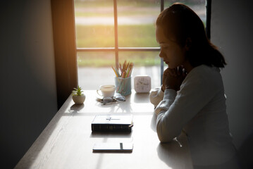 Pray and bible concept. Hand in hand together on bible. Asian woman (worship christian), thinking and closed her eyes. Person side view, female praying, hope for peace.