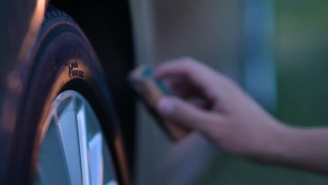 Close-up of cleaning a car wheel. A young man is using a sponge to blacken the rubber of a car wheel. Caring for a car