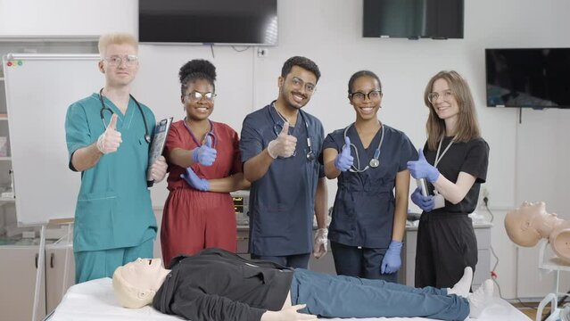 Group of medical professionals demonstrating first aid techniques in a clinic setting. Thumbs up