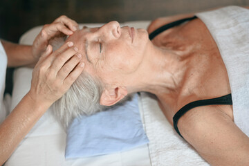Therapist is giving a massage to a senior woman lying on a massage table