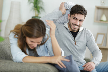 a happy couple is pillow fighting at home