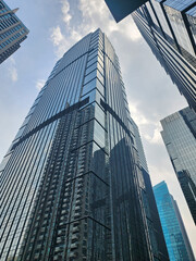 Low-angle view of a blue glas windwos skyscraper with a clear blue sky background. Business and finance concepts.