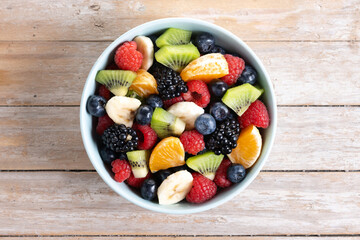 Fruit salad in a blue bowl on wooden table