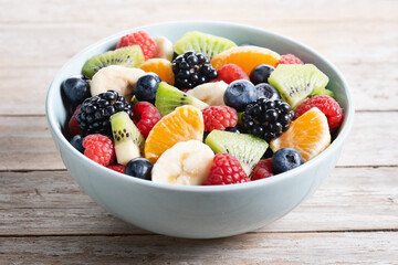 Fruit salad in a blue bowl on wooden table