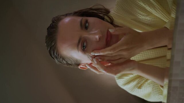 Vertical Screen: A woman touches her face in front of a mirror, seemingly concerned about pimples on her skin