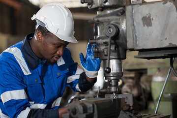 Male engineer worker working with lathe machine in industry factory, wearing safety uniform, helmet. Male technician worker maintenance parts of machine