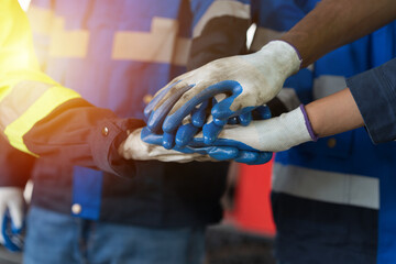 Group of male and female factory workers standing putting their hands together in industry factory. Factory workers stack of hands in factory. Unity and teamwork concept