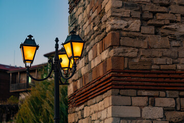 A lamp in the Old Town of Nessebar, Bulgaria. Brick walls behind the lamp. Vintage image.