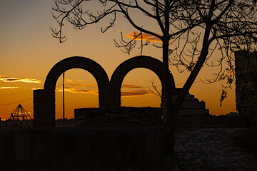 Beautiful orange sunset sky between two vintage old town arches from a city structure. 