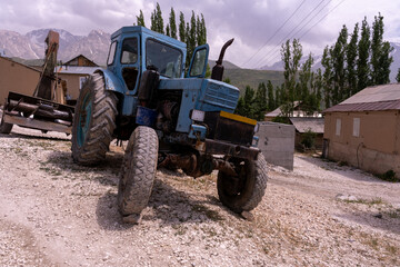 Obraz premium A blue tractor with black tires is parked in a dirt field