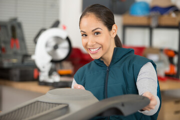 happy woman technician standing with wheel at auto workshop