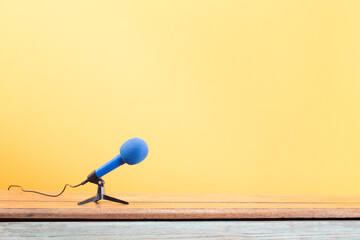Microphone for press conference or interview on the wooden desk front yellow wall background. Retro...