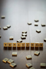 Word Sanctions made of wooden block letters with coins stacks