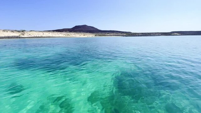 Crystal clear ocean water with volcano in the background and white sand beach, Baja California Sur, Mexico . Isla Coronado