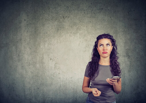 Portrait of a beautiful young woman with cellphone feeling annoyed looking up 