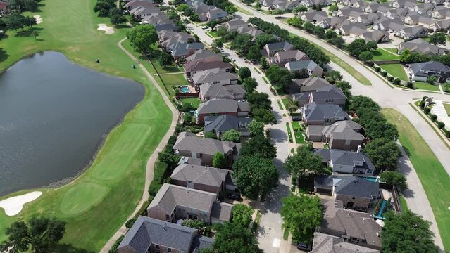 Club cars moving in residential golf course along upscale large mansion houses with concrete titles roof, swimming pool, wealthy part of North Plano, Dallas Fort Worth Metroplex Texas, flyover